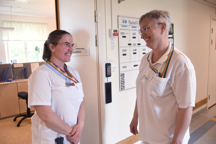 Lisa i sjukhuskläder talar med kollega