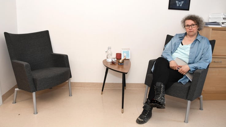 En person som sitter på en stol i ett rum.