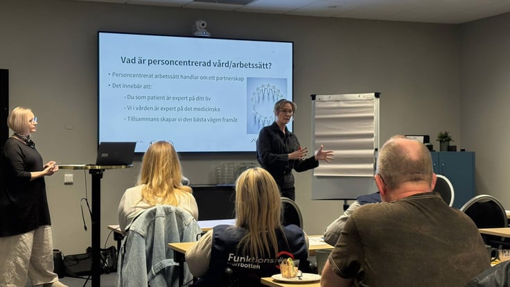 En grupp människor som står framför en projektorduk.