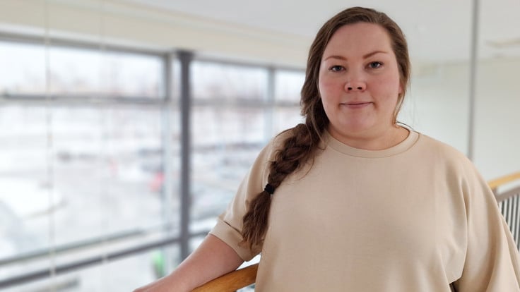 En kvinna i en beige skjorta står på en balkong.