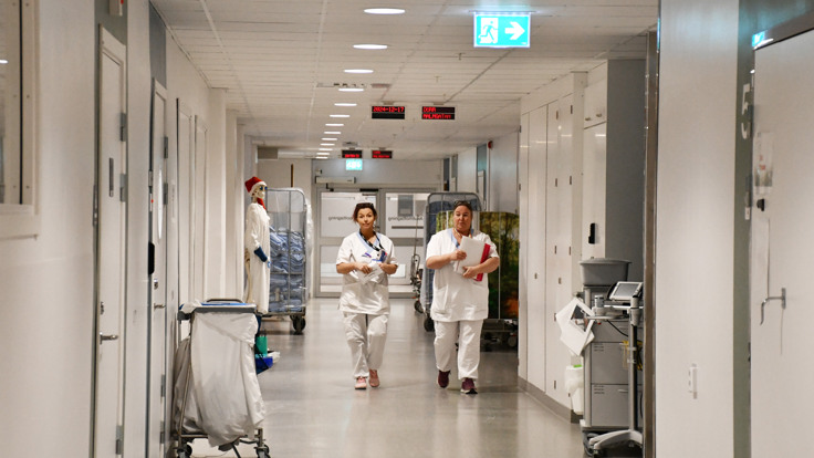 Två sjuksköterskor som går längs en sjukhuskorridor.