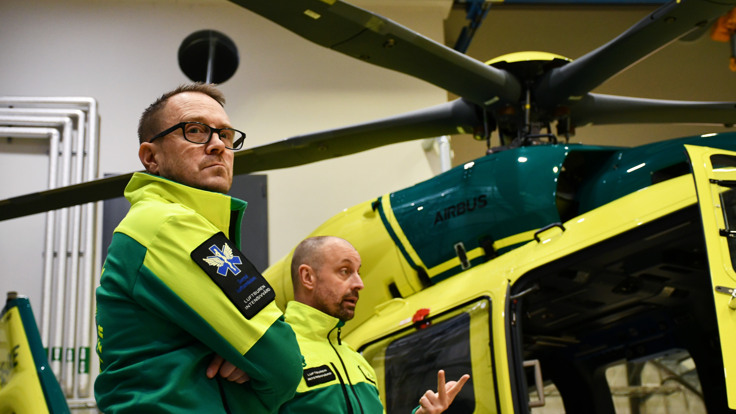 Två män som står framför en helikopter.