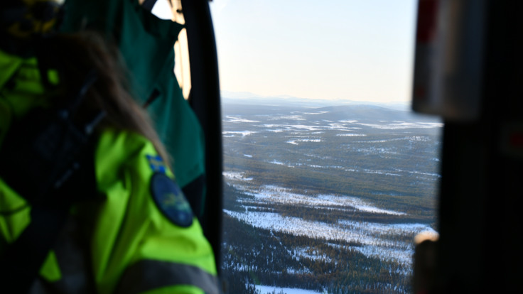 En utsikt inifrån en helikopter över ett snötäckt landskap.