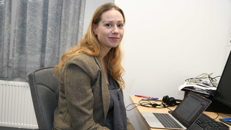En kvinna som sitter i en stol framför en dator.