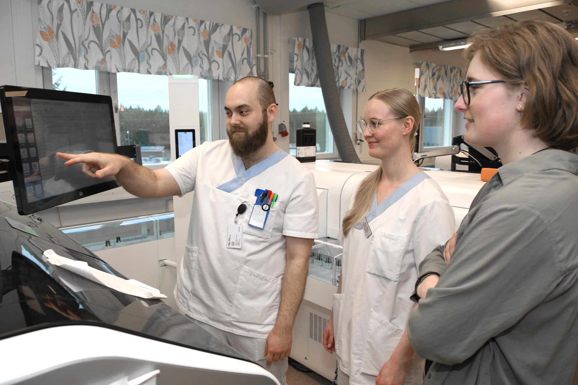 Nyblivna biomedicinska analytikerna Sam Holmberg, Elida Björk och Julia Grönlund vid laboratoriemedicins automatbana.