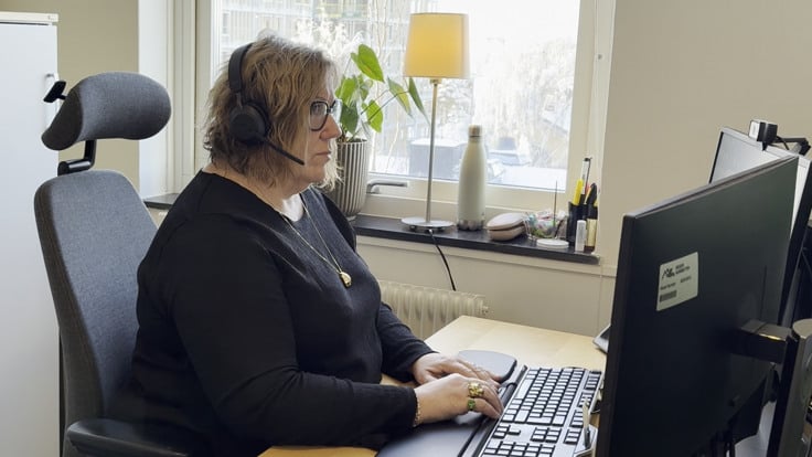 En kvinna sitter vid ett skrivbord och använder en dator.