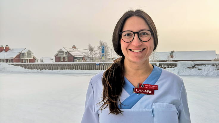 Carolina, iklädd vita arbetskläder, står utomhus i ett snöigt Kiruna.